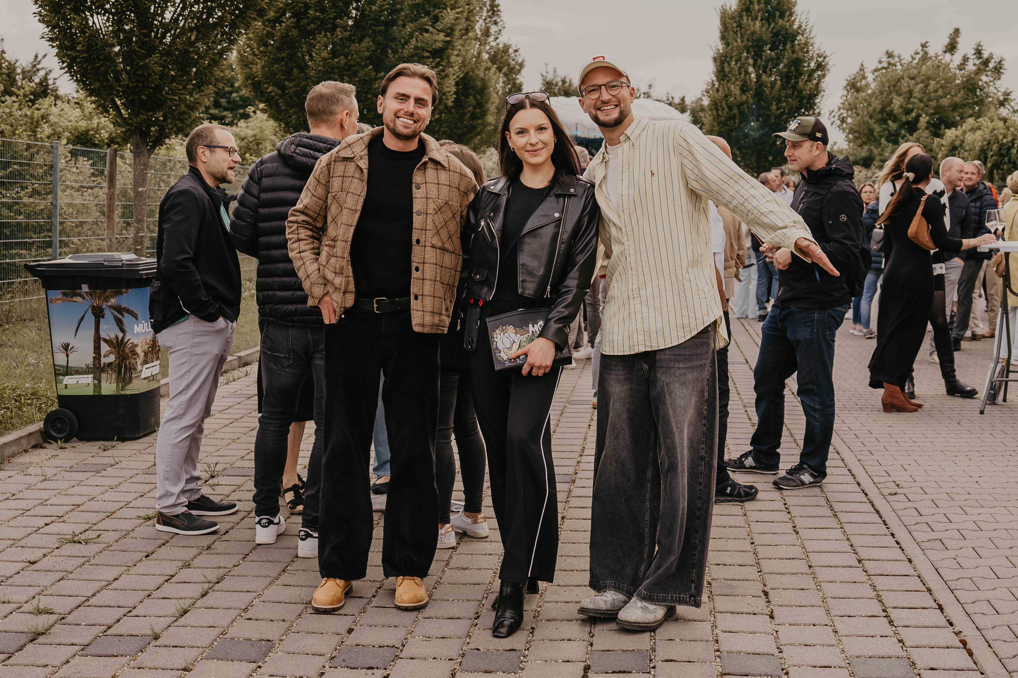 Drei Gäste posieren gemeinsam vor dem Eingang der House Art Vernissage