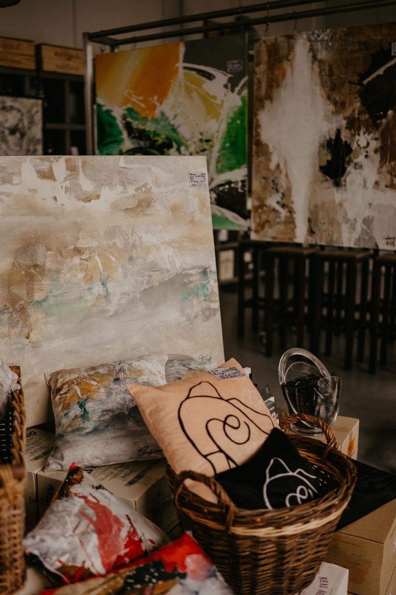 Gemälde und Kunstmerchandise mit Kissen und Weidenkorb bei der House Art Vernissage