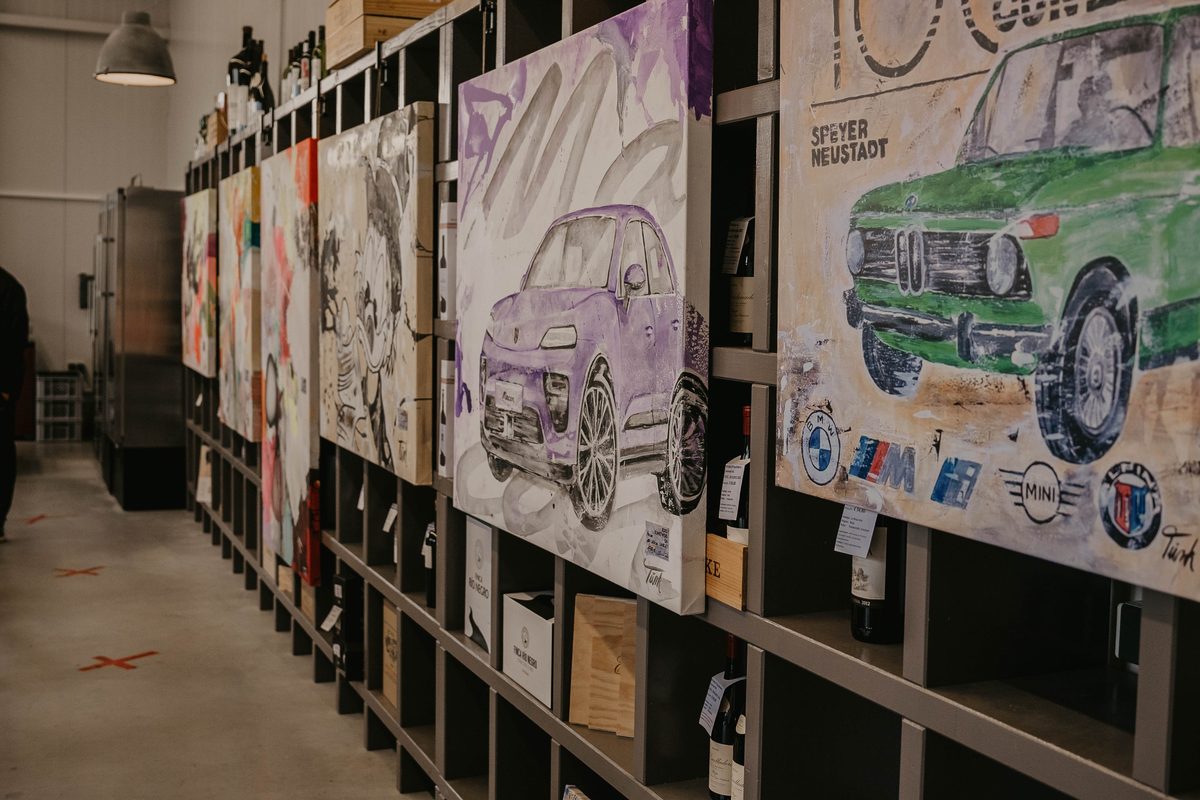 Reihe von Sabine Türks Gemälden mit Automobil-Motiven in den Weinregalen der House Art Galerie