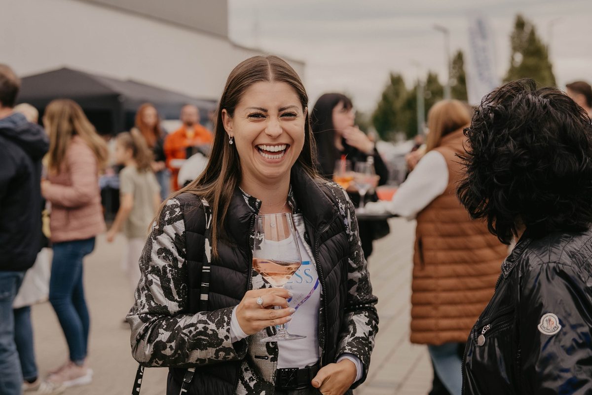 Lachende Besucherin mit einem Glas Roséwein beim House Art Outdoor-Event